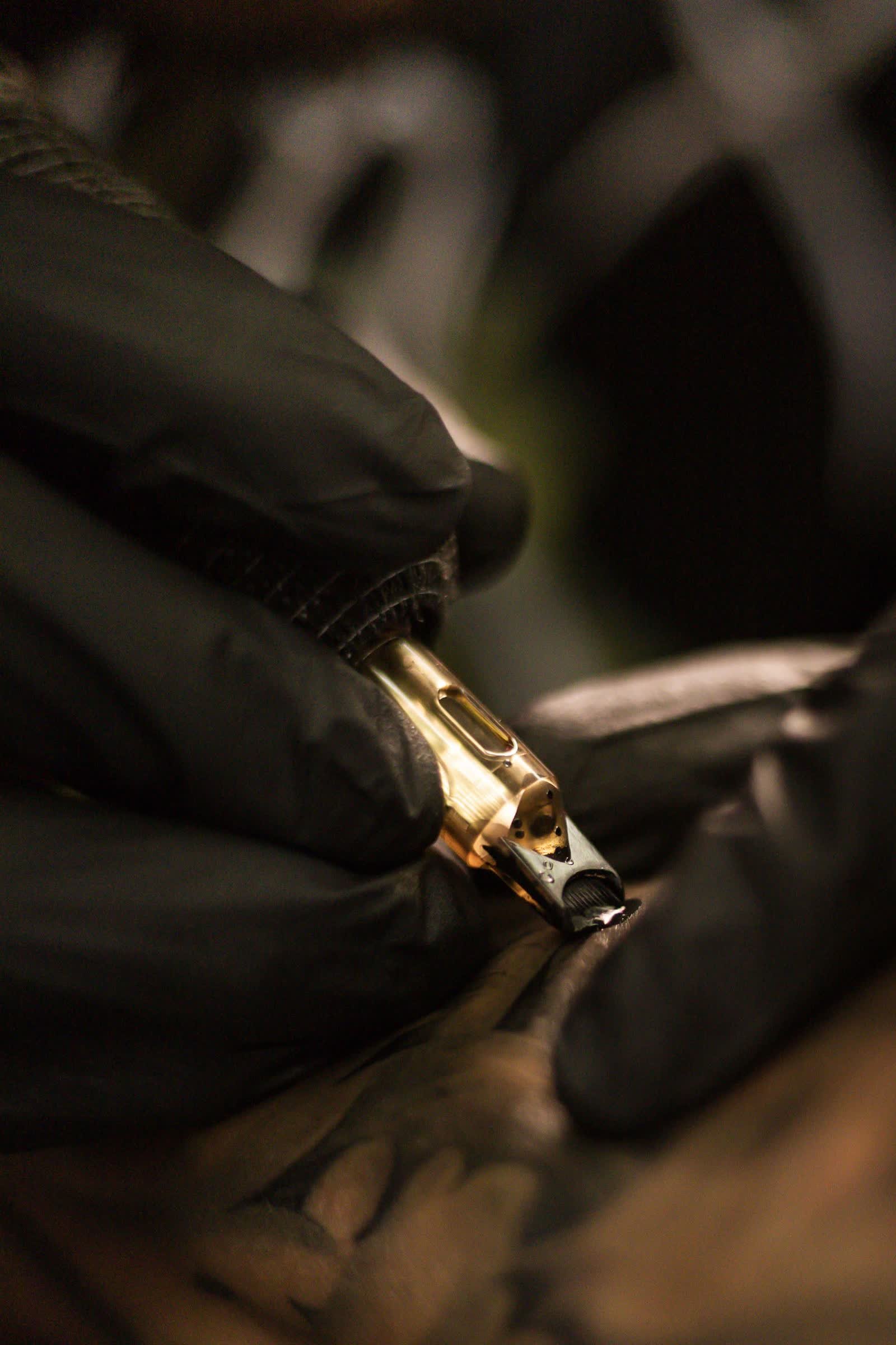 Máquina de tatuagem em detalhe, luvas pretas